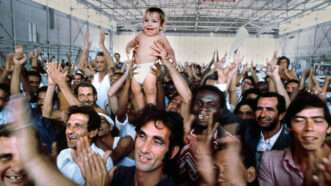 Mariel Boat Lift refugees holding up a child | Photo: The Mariel refugees pictured on an Air Force base in Florida; Tim Chapman/Miami Herald/Getty