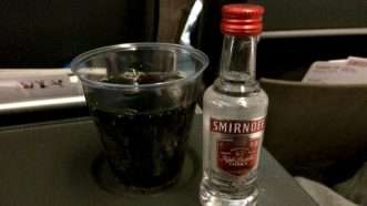 A miniature bottle of Smirnoff vodka with a cup of soda, on an airline passenger tray. | Christian Heinz | Dreamstime.com