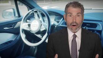 John Stossel is seen with a self-driving car in the background | Stossel TV