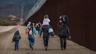 A group of asylum seekers walk along the U.S.-Mexico border near San Diego, California | Qian Weizhong/VCG/Newscom