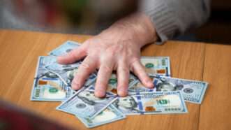 A man's hand and a stack of U.S. hundred-dollar bills | Devinpavel | Dreamstime.com