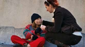 Woman giving food and clothing to another homeless woman | Photo 23056919 © Landd09 | Dreamstime.com