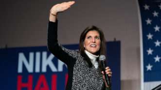Former South Carolina Gov. Nikki Haley waves to supporters as she either enters or exits a stage with her campaign sign in the background. | Sean Rayford/ZUMAPRESS/Newscom