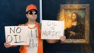 Protester Remy holds up anti-oil signs in front of the Mona Lisa splashed with soup | Reason TV