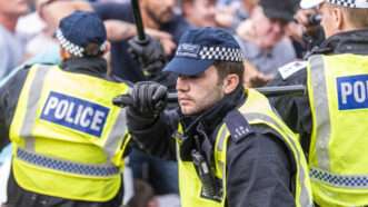 A London police officer holding a billy club over one shoulder, during a fracas. | Avpics | Dreamstime.com
