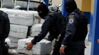 Masked policemen in Honduras unload wrapped kilos of cocaine from a truck. | STR/EFE/Newscom