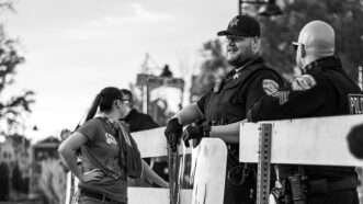 Police officers standing near a barricade | Photo: Cooper Baumgartner/Unsplash