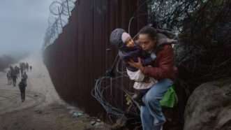 Migrants pictured along the U.S.-Mexico border fence | Qian Weizhong/VCG/Newscom