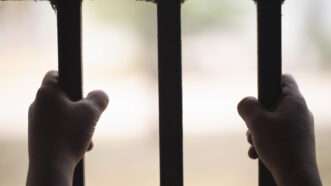 A child's hands clutch prison bars. | Tinnakorn Jorruang | Dreamstime.com