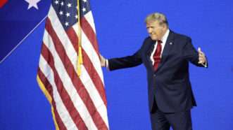 Former President Donald Trump moves on the American flag with arms open, on stage at the 2024 Conservative Political Action Conference in National Harbor, Maryland. | Abaca Press/Gripas Yuri/Abaca/Sipa USA/Newscom