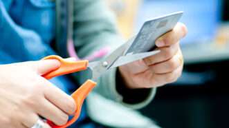A person using scissors to cut up a credit card | Photo 27246429 © Sixninepixels | Dreamstime.com