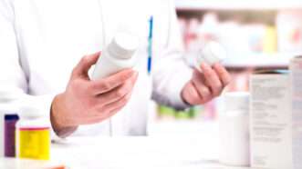 A pharmacist compares two bottles of pills. | Tero Vesalainen | Dreamstime.com