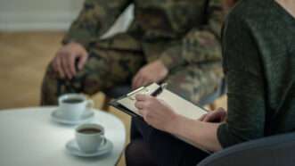 A soldier in military fatigues sits with a therapist. | Katarzyna Bialasiewicz | Dreamstime.com