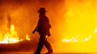 A firefighter walks away from a blaze. | Arisha Singh | Dreamstime.com