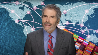 John Stossel stands in front of a map of the world | Stossel TV