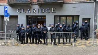 A large gaggle of blue-clad police officers barricade the entrance to the NatCon Brussels 2 conference at the gray-walled Claridge event space in Belgium. | Paul Coleman