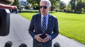 Biden talks to the press pool while standing outdoors and wearing aviator sunglasses | Tom Williams/CQ Roll Call/Newscom