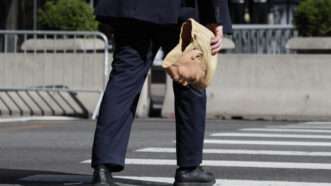 A person crossing the street holding a rubber Donald Trump mask |  John Angelillo/UPI/Newscom