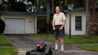 Man stands with a lawn mower in front of his home. | Institute for Justice