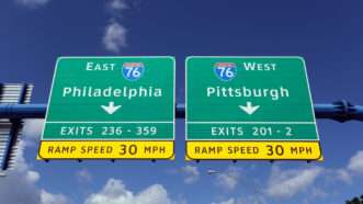 Interstate highway exit signs, one depicting an exit to Interstate 76 east toward Philadelphia, the other for an exit to Interstate 76 west toward Pittsburgh. | Wellesenterprises | Dreamstime.com