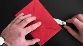 Close-up of a man's hands opening an envelope with a letter opener. | Christian Horz | Dreamstime.com