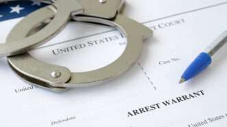 Handcuffs and a ballpoint pen on an arrest warrant. | Mykhailo Polenok | Dreamstime.com