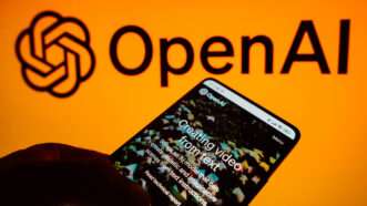 Open AI app on smartphone, in front of a larger company logo | Rafael Henrique/ZUMAPRESS/Newscom