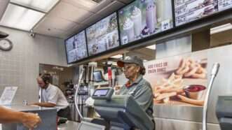 Fast food worker stands behind the counter | imageBROKER/Ron Buskirk/Newscom