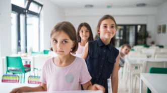 School children queue up with trays in the cafeteria. | Pojoslaw | Dreamstime.com