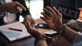 Close-up of an arrestee's hands, with wrists handcuffed, as a police officer points | Wutthichai Luemuang | Dreamstime.com 