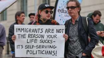 A protestor holds a sign that reads, "IMMIGRANTS ARE NOT THE REASON YOUR LIFE SUCKS - IT'S SELF-SERVING POLITICIANS!" | News Images/ZUMAPRESS/Newscom