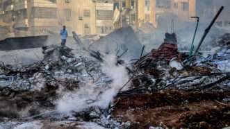 A Lebanese man stands among rubble, debris and smoke that is still billowing from the site of the massive Israeli air strike that killed pro-Iranian Hezbollah chief Hassan Nasrallah in Beirut's southern suburb. | SANDRO BASILI/OLA NEWS/SIPA/Newscom