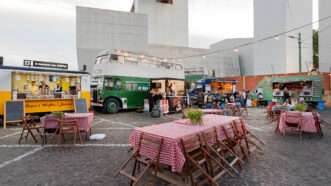 Tables and tablecloths set up in a parking lot, surrounded by food trucks. | Radiokafka | Dreamstime.com