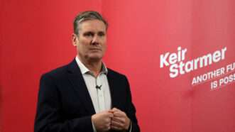 British Prime Minister Keir Starmer standing against a red backdrop with the text "Keir Starmer: Another Future Is Possible" at the edge | Dominic Dudley | Dreamstime.com