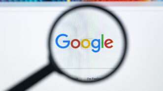 The Google logo is seen underneath a magnifying glass | ID 104313256 © Bigtunaonline | Dreamstime.com