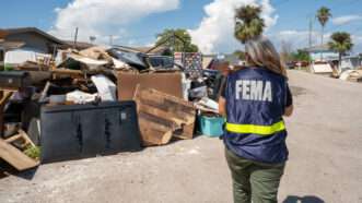 A person in a FEMA vest walking through a recent disaster zone. | Polaris/Newscom