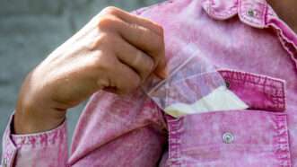 Close-up of a woman's hand taking a baggie of cocaine out of the breast pocket of her shirt. | Edgars Sermulis | Dreamstime.com