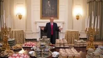 Donald Trump standing in front of a table full of fast food | Everett Collection/Newscom