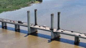 Wide shot from above of motor vehicle traffic on a bridge over water, in Porto Alegre, Brazil. | Cristian Lourenco | Dreamstime.com