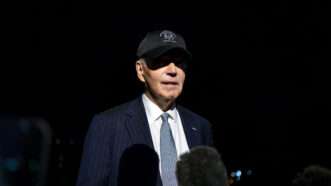 President Joe Biden takes questions from reporters, at night, wearing a baseball cap. | Bonnie Cash - Pool via CNP/CNP / Polaris/Newscom