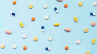 Tablets and capsules spread across a blue background | Photo: ediebloom/iStock