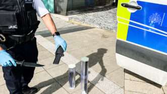 A London Metropolitican Police officer holds knives recovered in the course of an investigation. | Thabo Jaiyesimi/ZUMAPRESS/Newscom