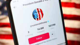 A smartphone open to the TikTok profile page of President Donald J. Trump. An American flag is in the background. | Thomas Fuller/ZUMAPRESS/Newscom