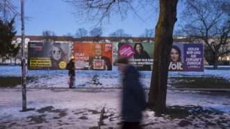 Pedestrians walk by a fence that bears election posters for the February 2025 German elections. | imageBROKER/Ben Kriemann/Newscom