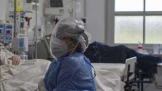 A medical provider sits in a hospital room in full personal protective equipment | Wirestock | Dreamstime.com