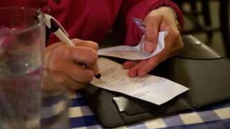 A restaurant patron fills in the tip portion of their bill. | Rtdeleon04 | Dreamstime.com