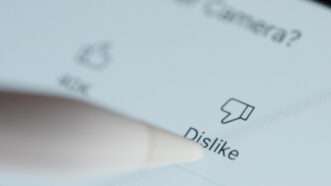 In an extreme closeup, a stylus prepares to mark "Dislike" on a YouTube video. | Dimarik16 | Dreamstime.com