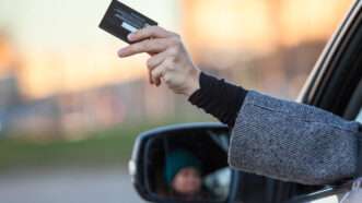 A person holding a credit card out a car window. | ID 204722913 © Andrey Kekyalyaynen | Dreamstime.com