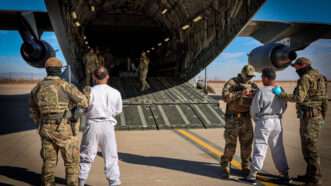 US military personnel loading detainees onto a plane | DEPARTMENT OF HOMELAND SECURITY/UPI/Newscom