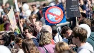 A protest at Germany's Brandenburg Gate. One protester holds a sign with a circle and line through the logo for AfD. | Fabian Sommer/dpa/picture-alliance/Newscom